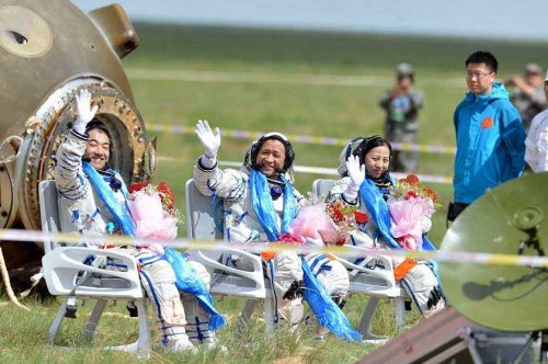 Astronauts Zhang Xiaoguang, Nie Haisheng and Wang Yaping (from left to right) wave after getting out of the re-entry capsule of China's Shenzhou-10 spacecraft following its successful landing at the main landing site in north China's Inner Mongolia Autonomous Region on June 26, 2013. (Photo/Xinhua)