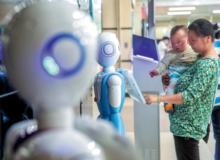一位女士通过广州第二省级综合医院的机器人检查医疗信息。 医院在诊断，医学影像和物流等多个领域采用人工智能技术。 （谭清菊摄/中国日报）
