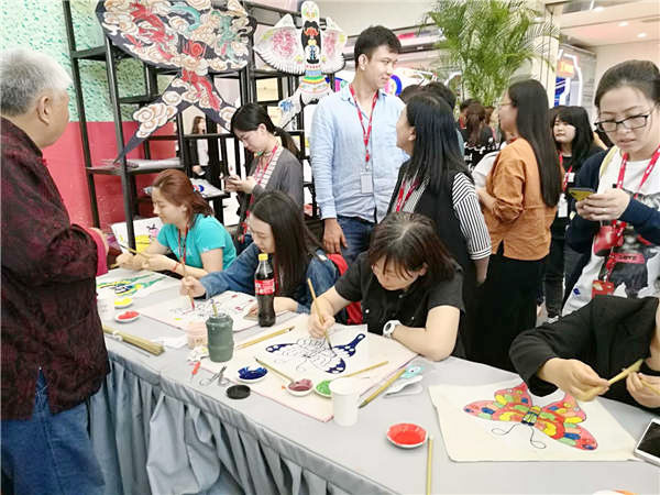 Folk artist Luo Huanwen teaches visitors to make kites.(Photo provided to chinadaily.com.cn)
