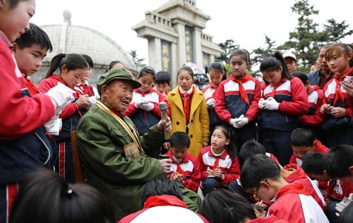 Ma Ruying, a veteran who fought in the War of Resistance Against Japanese Aggression (1931-45), shares his memories about the war with students at a cemetery in Lianyungang, Jiangsu province, on April 5, Tomb Sweeping Day. (Si Wei/For China Daily)