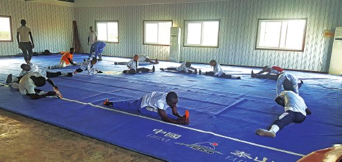 Students of the Chinese Wushu School in Monrovia, Liberia, stretch during daily practice. (Photo provided to China Daily)