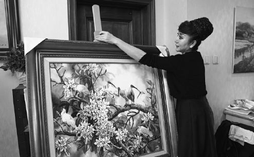 Yan Zi narrates a story about her life-changing encounter with crested ibis while displaying one of her paintings at her home in Xi'an.  (Photo by Huo Yan/China Daily)
