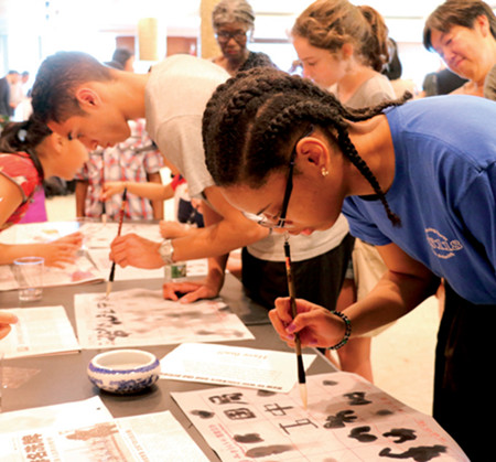 Sheridan Cole, a 13-year-old student from MS 118 in the Bronx, New York, writes Chinese calligraphy at China Open Day. (Photo/CHINA DAILY)