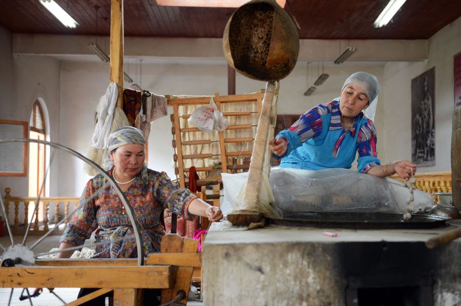Two Atlas silk masters work together to spin thread at a workshop in Jiya village. (Photo/Xinhua)