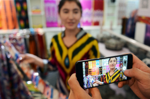 A sales woman displays silk products at a Atlas silk workshop in Jiya village. (Photo/Xinhua)