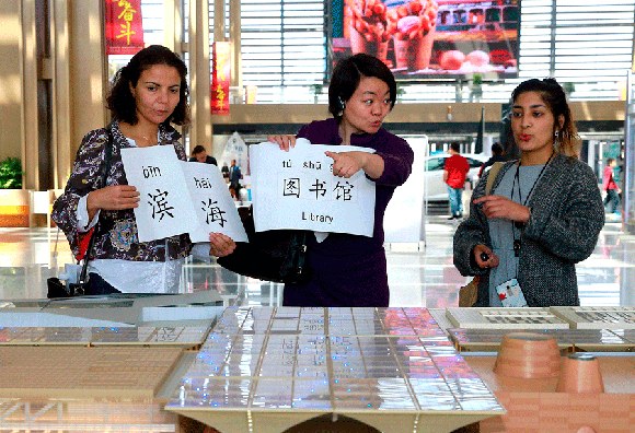 Hager Braham from Canada (left) and Jyotika Chauhan (right) from South Africa learn Chinese while visiting Binhai Cultural Center during a language program launched by a community school in the Tianjin Economic-Technological Development Area. Photo for China Daily/ Jia Chenglong)