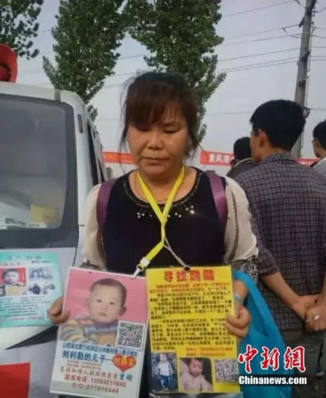 The boards Chen Zhen carries provide detailed information of her missing son, Pengpeng. (Photo/chinanews.com)