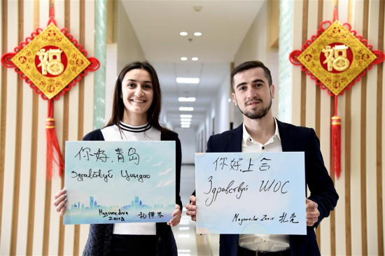 Russian student Zakir (R) and his sister Zaira, both studying in China University of Petroleum, display boards with Chinese and Russian handwritings of Hello Qingdao and Hello SCO, in Qingdao, the host city of the Shanghai Cooperation Organization (SCO) Summit, in east China's Shandong Province, May 3, 2018. (Xinhua/Guo Xulei)