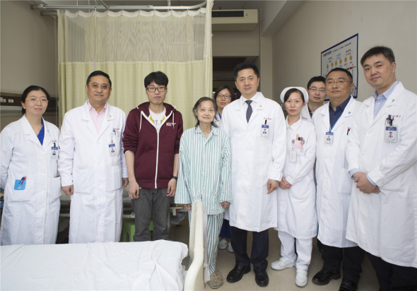 Mr Xie and his mother pose for a picture with medical staff from Zhongshan Hospital on May 10, before they were discharged from the hospital. （Photo provided to chinadaily.com.cn）