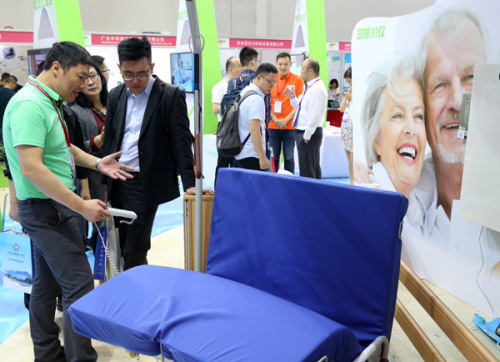 An exhibitor shows a therapeutic bed to visitors at the China International Senior Services Expo in Beijing on May 9, 2018.(Photo by Feng Yongbin/China Daily)