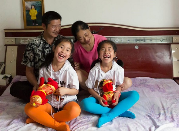 Ding Jiaxing and his wife, An Ping, pose with their 7yearold twin daughters Ding Siqi (left) and Ding Sihong, who were born after the Wenchuan earthquake, in their home in Beichuan county, Sichuan province, on Monday. A photo of An’s elder daughter, who died in the earthquake 10 years ago, is on the bed’s headboard. (Zou Hong/China Daily)