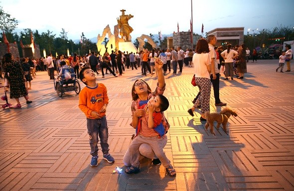 A resident plays with her children on a square in the new Beichuan county earlier this month. (Zou Hong/China Daily)