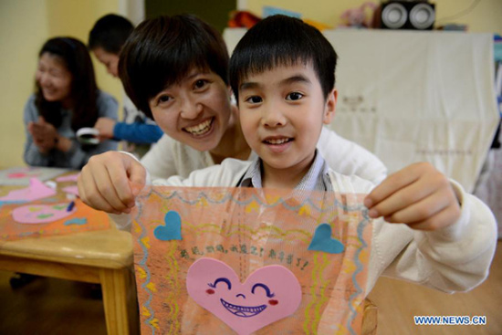 A boy presents a handkerchief he made for his mother at a kindergarten in Hefei, capital of East China's Anhui province, May 9, 2013. Children made cards, handkerchiefs and other gifts for their mother to celebrate the coming Mother's Day. (Photo/Xinhua)