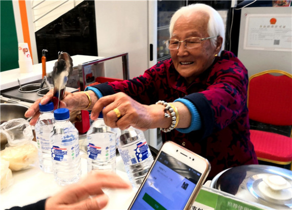 Jiang Naijun, 98, works at the 97 Supermarket she opened in July, in Changchun, Jilin province.(Photo provided to China Daily)