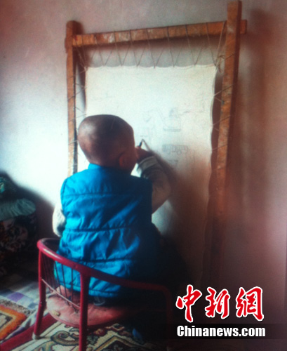 Their three-year-old son unconsciously imitates his parents, holding a brush to paint on the silk.