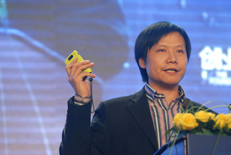 Lei Jun, chief executive officer of Xiaomi Corp, holding his company's mobile smartphone while speaking at a meeting. [Photo/China Daily] 