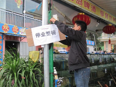 A worker puts up a notice saying business closed outside the Fulin Fishing Village Seafood restaurant in Sanya, Hainan province, on Sunday, after it was accused by tourists of overcharging customers. [Photo/China Daily] 