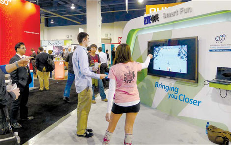 Visitors at a consumer technology exhibition in Las Vegas play a video-tennis game on a SmartTV produced by the Chinese IT giant ZTE Corp. [China Daily]
