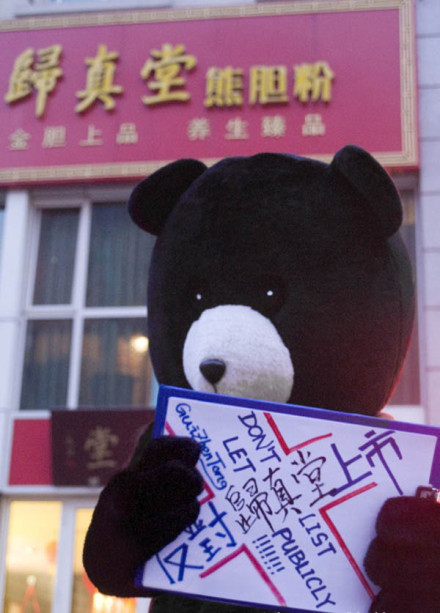 A photo posted on Sina Weibo, a Chinese micro-blogging service, shows a protester wearing a bear costume and holding an anti-Guizhentang sign in front of a Guizhentang store. [Photo/weibo.com]