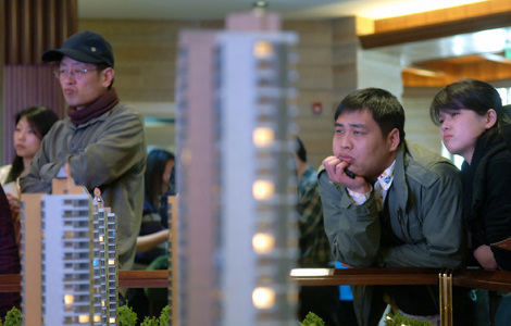 Potential homebuyers examine a developer's model in Beijing. Last year, more than 200 foreign property enterprises exited the Beijing property market as conditions turned sluggish. [Photo / Xinhua]