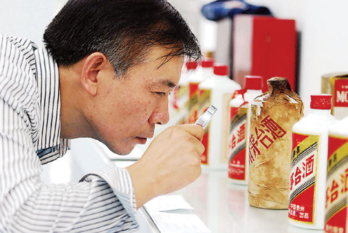 A prospective buyer takes a closer look at a vintage bottle of Moutai during an auction in Nanchang, Jiangxi province last year. [Chinadaily]