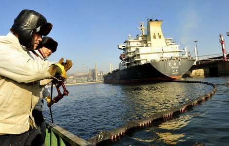 Workers prepare to prevent an oil spill as a tanker docks at Dalian port in Liaoning province. China might develop its own ocean-going shipping system for crude imports. [Photo / China Daily]