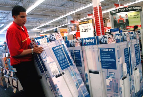 A shop assistant adjusts a Haier air conditioner in a store in Queens, New York.