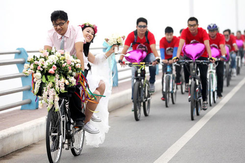 Chen Liang rides a bike carrying his bride, Wang Qian, during their eco-friendly wedding ceremony in Linyi, Shandong province, on Friday. Accompanied by nearly 60 bicycle riders, the newlyweds pedaled through city streets in honor of World Car Free Day,  