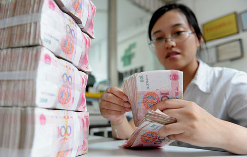 A bank employee counts money at a branch in Lianyungang, Jiangsu province. [Photo/China Daily] 