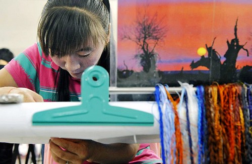 A Chinese worker hunches over a sewing machine, making made-in-China products. (Photo/Xinhua)