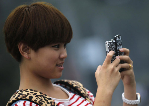 A girl holds two mobile phones as she takes pictures at a downtown area of Shanghai, Oct 22, 2012. [Photo/Agencies] 