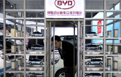 A BYD Co Ltd employee checks a model of a charging station at the 2012 Beijing International Automotive Exhibition in the capital city in April. The battery and electric carmaker has warned that profits for 2012 are expected to drop dramatically due to a slumping domestic market. [Photo/Agencies]