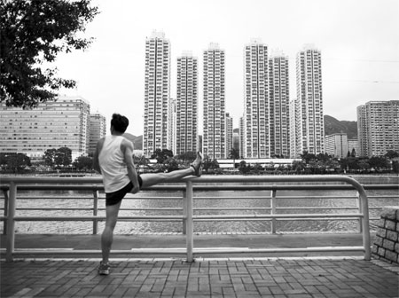 A man exercises in front of residential buildings along the Shing Mun River in Sha Tin. The city's second-hand home prices hit a new high point for the six consecutive week last week. [Photo/Agencies]