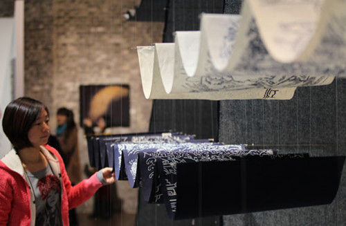 A visitor inspects an art work using fabric at the 7th 'From Lausanne to Beijing' International Fiber Art Biennale and Symposium on Nov 8, 2012. [Xu Congjun / Asianewsphoto] 