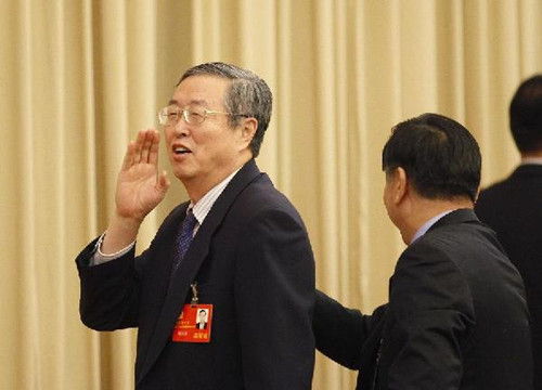 Zhou Xiaochuan, governor of the People's Bank of China (PBOC), gestures to media reporters while leaving the venue after a group discussion of the delegation of finance sectors to the 18th National Congress of the Communist Party of China (CPC) in Beijing