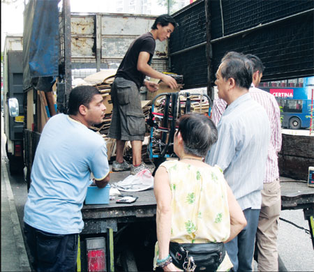 Sam and his staff attend to his customers at one of their meeting points in Wong Tai Sin. [Photo/China Daily] 