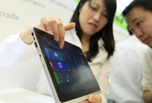 An attendant demonstrates how to use an Acer Inc Iconia W700 tablet device at a news conference in Taipei. Acer expects devices running Microsoft Corp's Windows 8 software to start contributing to its revenues in August as the Taiwan's largest computer maker starts shipments ahead of the official release. [Photo/Bloomberg] 