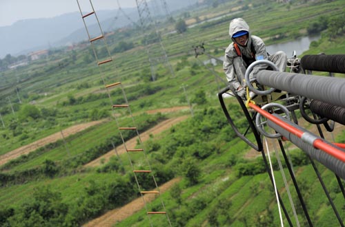 A man works on an ultra-high voltage transmission tower in Hong'an county in Hubei province. [Photo/China Daily] 