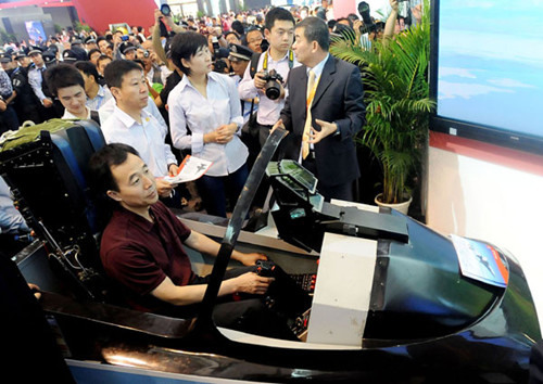Astronauts Jing Haipeng (in the aviation simulator), Liu Wang (second left, second row) and Liu Yang (central, second row) try the aviation simulator of the Lieying L15 advanced trainer at the Ninth China International Aviation and Aerospace Exhibition in Zhuhai, Guangdong province, on Wednesday. CHEN LIANG / FOR CHINA DAILY