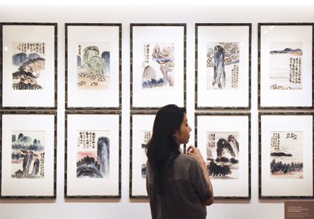 A woman inspects artwork by Chinese artist Qi Baishi entitled Landscapes during a China Guardian auction preview in Hong Kong. [Photo/Agencies]