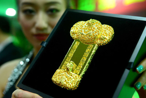 A sales assistant shows gold ornaments at a store in Beijing on Monday. A World Gold Council report says that gold demand will pick up in China after a decline in the third quarter. AFP PHOTO