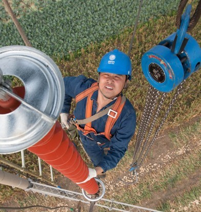 A State Grid Corp employee works on a transmission tower in Huaibei, Anhui province. [Photo/China Daily] 