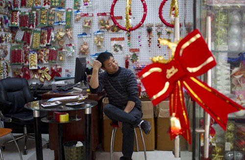 A shopkeeper waits for customers in Yiwu, Zhejiang province. Christmas orders have fallen, and foreign buyers no longer come in droves to talk shop with the many thousands of factory owners in this manufacturing powerhouse in East China. [Photo/China Daily] 