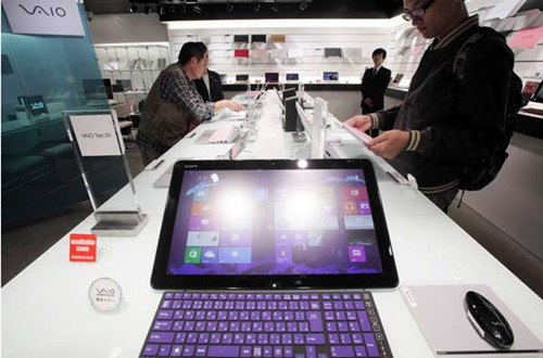 Customers examining notebooks at a Sony store in Tokyo. Many Japanese electronics companies have cut or are going to cut their payrolls because their businesses are in the red. [Provided to China Daily]
