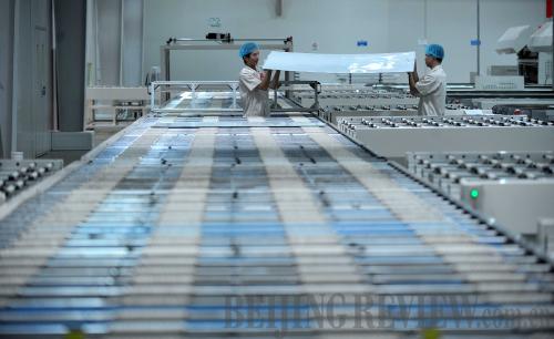 IN THE PLANT: Workers in Hainan Yingli Group operate the assembly line of solar cells on August 22, 2012 (GUO CHENG)