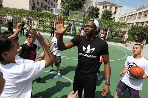 Dwight Howard, basketball player for the Los Angeles Lakers of the National Basketball Association, shoots hoops with students at the Changning Primary Vocational School of Shanghai. Provided to China Daily 