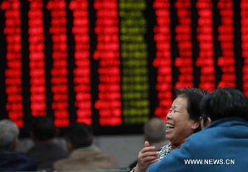 A stock investor smiles in front of an electronic board showing rising stock prices at a trading hall in Shanghai, east China, Dec. 14, 2012. Chinese shares surged more than 4 percent on Friday as investors have high expectations for an annual economic conference that will set the tone for China's economic policies in 2013. The benchmark Shanghai Composite Index climbed 4.32 percent, or 89.15 points, to end at 2,150.63. The Shenzhen Component Index finished at 8,530.9, up 4.4 percent, or 359.55 points. (Xinhua/Pei Xin)