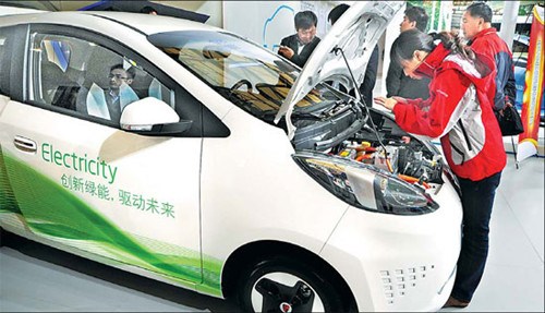 Visitors at a trade show in Shanghai inspect a Roewe E50 electric vehicle. The local government is providing free license plates and rebates to residents who buy electric cars. According to experts, recharging stations are being added around the city to help support the industry. [Photo/China Daily]