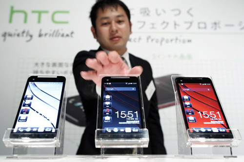 An employee adjusting a row of HTC J Butterfly smartphones, produced by HTC Corp, during a launch event in Tokyo on Nov 20. Taiwan's HTC Corp needs to improve its global brand awareness to gain a share in the Chinese mainland. Its newly unveiled model is likely to help the vendor to do that. [Photo / China Daily]