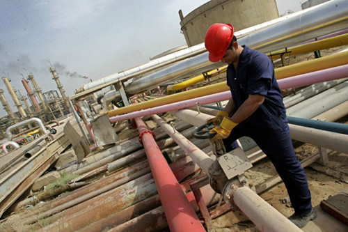 A worker adjusts a control valve at an oil refinery in Baghdad, Iraq. China will become a major consumer of Iraq's oil and will continue to invest substantially in Iraqi oil production infrastructure, according to the International Energy Agency. [Photo/Agencies]